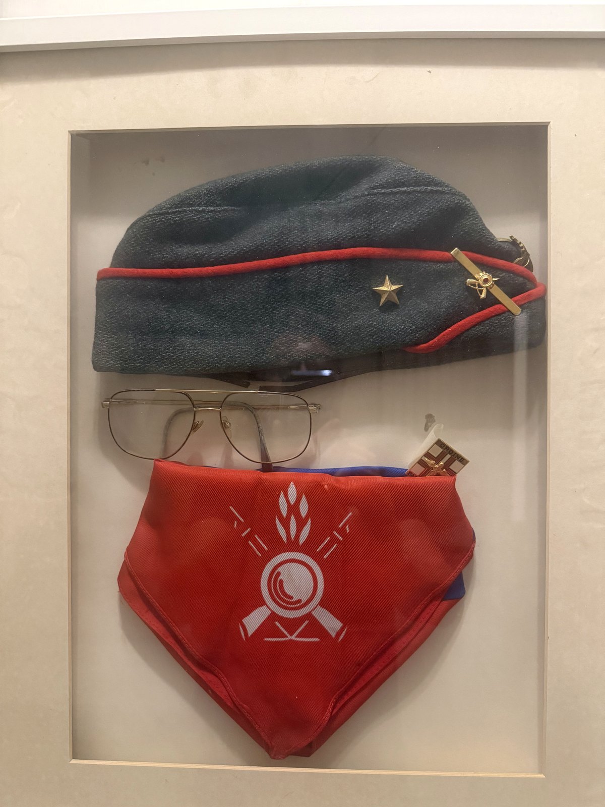 Quadro commemorativo dedicato a Giovanni Mortari con cappello da fante, occhiali, spilla da farmacista e sciarpa rossa